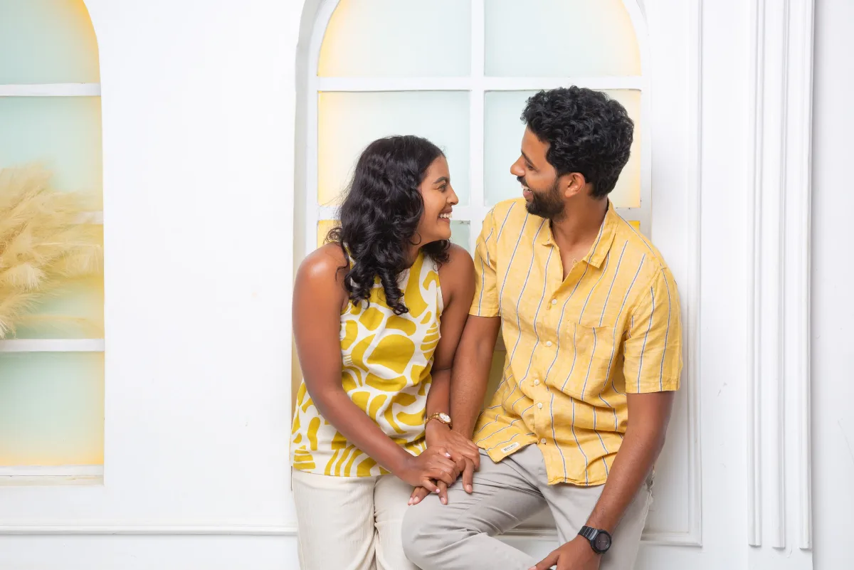 Ashley and Khush smiling at each other in front of a sunlit window